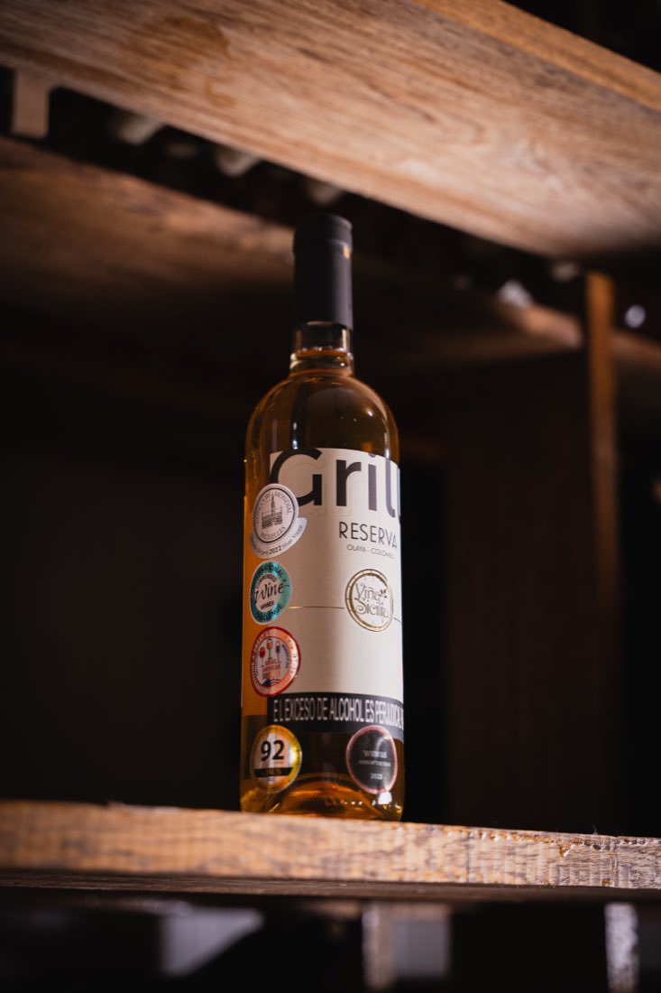 Botella de vino fotografiada sobre estantería de madera.