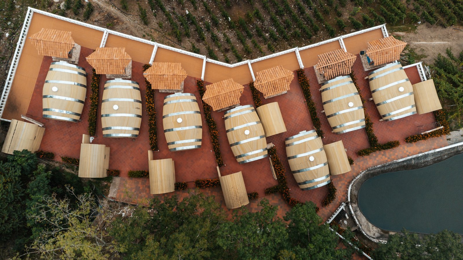 Vista cenital con dron del conjunto de cabañas-barrica junto al embalse.