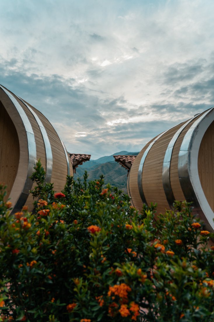 Dos cabañas-barrica enmarcando la montaña al atardecer.