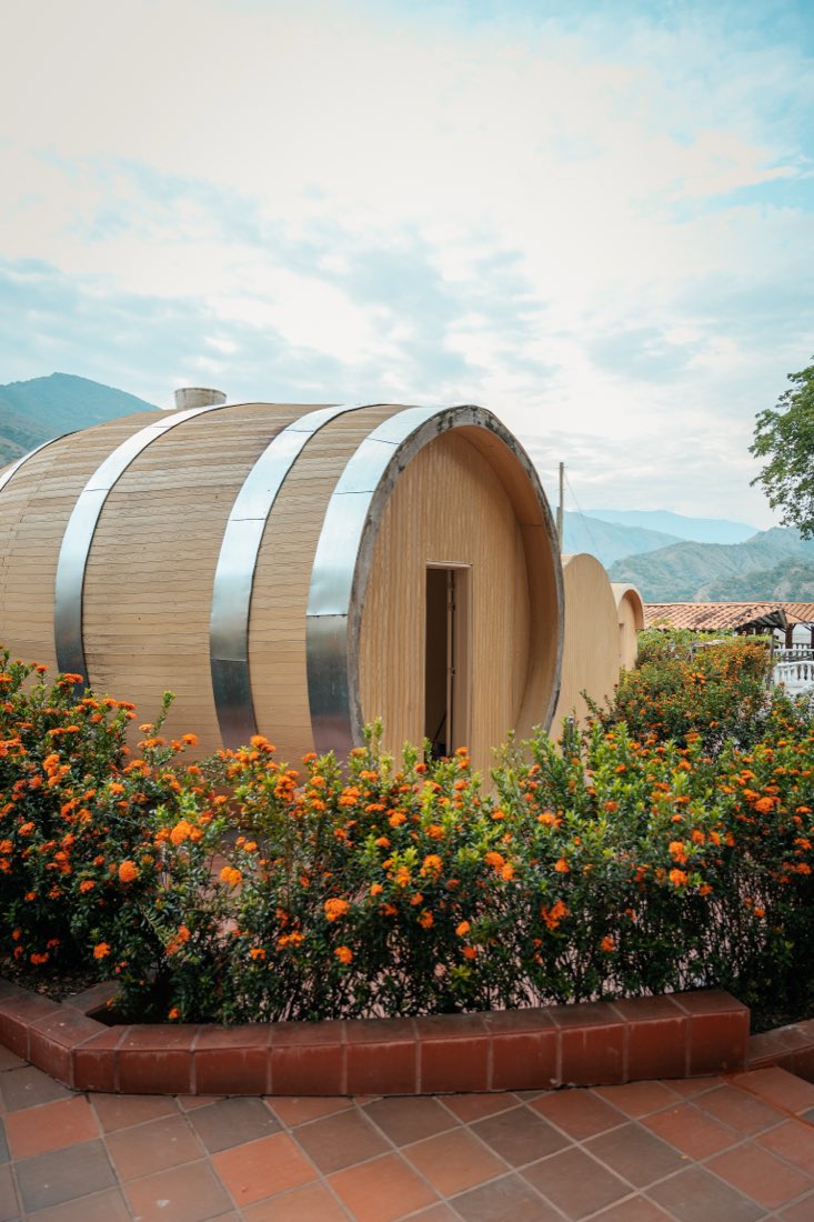 Cabaña-barrica rodeada de flores naranjas.