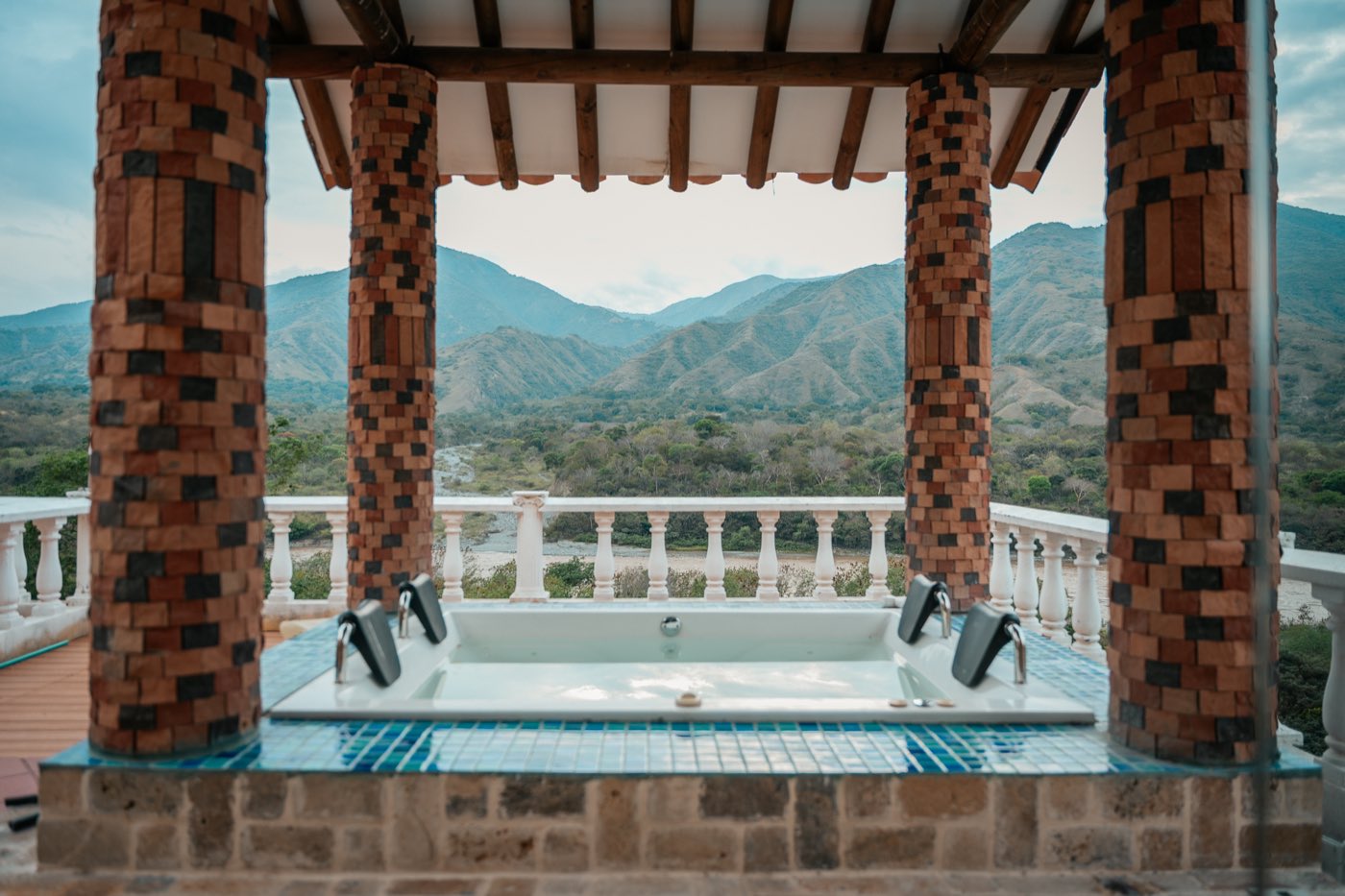 Jacuzzi bajo pérgola de ladrillo con vista al valle.